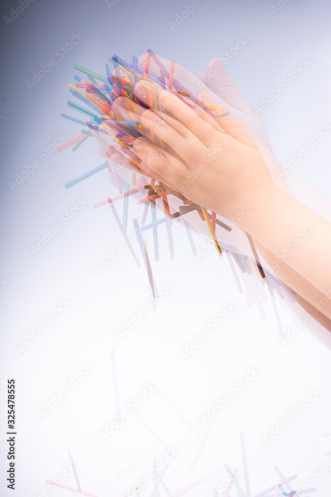 Fototapeta Hand letting coloured wooden sticks drop on white
