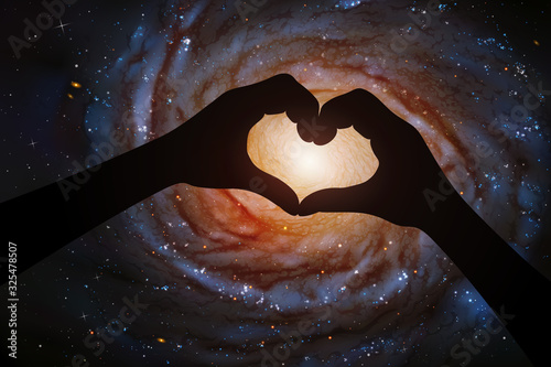 Spiral galaxy in heart shaped hands of astronaut in space. Romantic vector illustration with hand silhouette and astronomical object in cosmos. Elements of this image furnished by NASA