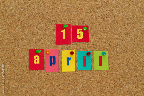 April 15 written on colorful sticky notes pinned on cork board. New year calendar. Tax day. photo