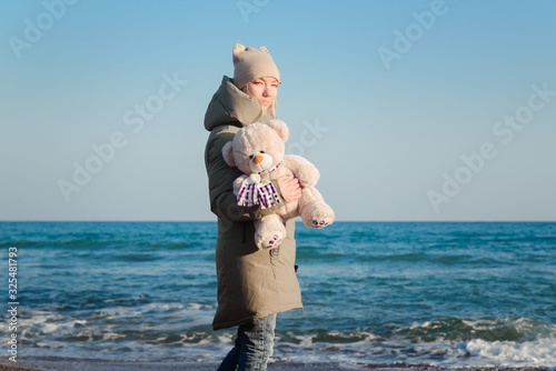Girl with a teddy bear in hand on the seashore