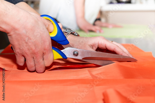 tailor cuts fabric with scissors