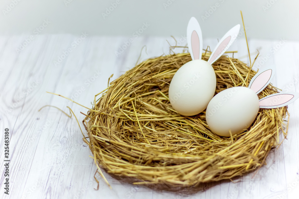 white Easter eggs with rabbit ears in the nest on a wooden table. side view white Easter eggs with rabbit ears in the nest on a wooden table. side view