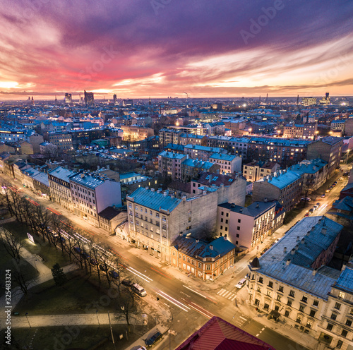 Fototapeta Naklejka Na Ścianę i Meble -  Aerial view of busy city in colorful sunset and street lights. Drone shot of Riga city.  