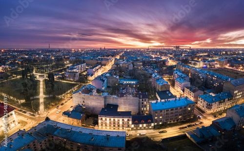 Aerial view of busy city in colorful sunset and street lights. Drone shot of Riga city. 