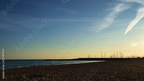 Beautiful timelapse of the coastal sunset with yellow and orange colors in the sky with a port in the background.