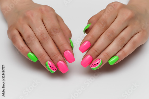 Summer pink and light green manicure with painted watermelons. Vacation manicure. Close-up on a white background. Acid colors of nails. Themed nails.