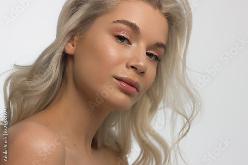 Closeup portrait of a woman with developing straight hair. Sweet tender young girl blonde. Natural lipstick, transparent clean skin. Skin care natural cosmetics in the spa salon or cosmetology.