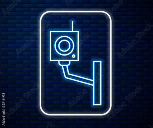 Glowing neon line Security camera icon isolated on brick wall background. Vector Illustration