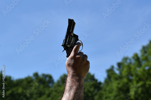 A man pointing to a clear blue sky with a gun before starting a race