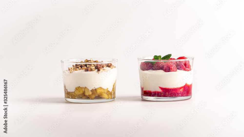 Two layered yogurt desserts. On with apple jam and pecan nuts, another with raspberry jam, fresh raspberries and mint. White background Two layered yogurt desserts. On with apple jam and pecan nuts, another with raspberry jam, fresh raspberries and mint. White background