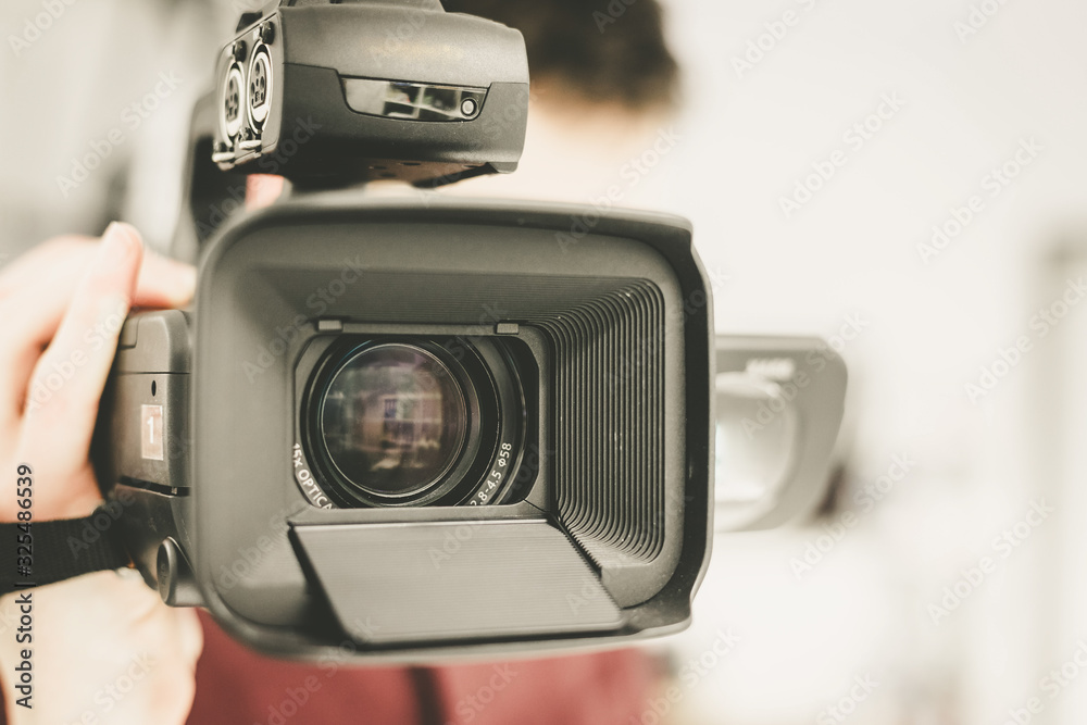 Professional film production: Male filmmaker is recording with a professional movie camera. Close up of camera lens. Professional film production: Male filmmaker is recording with a professional movie camera. Close up of camera lens.