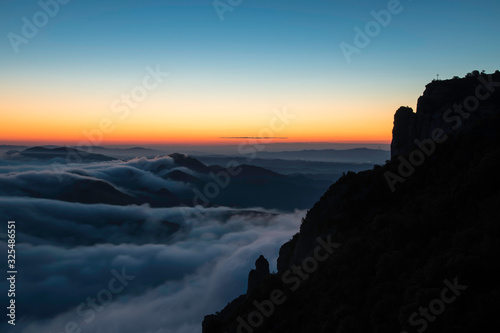 Landscape at sunrise in the cloudy mountains with blue colors and orange horionte, Montserrat, Spain