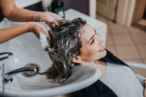 Professional hairdresser washing hair of a beautiful young  woman in hair salon. .