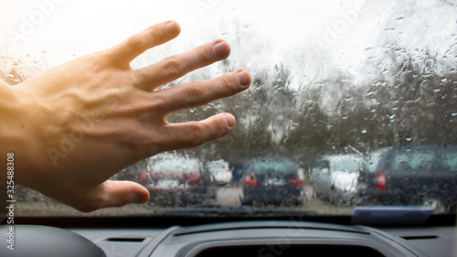 Hand on a wet car window. Raindrops outside the window. Rainy weather outside.