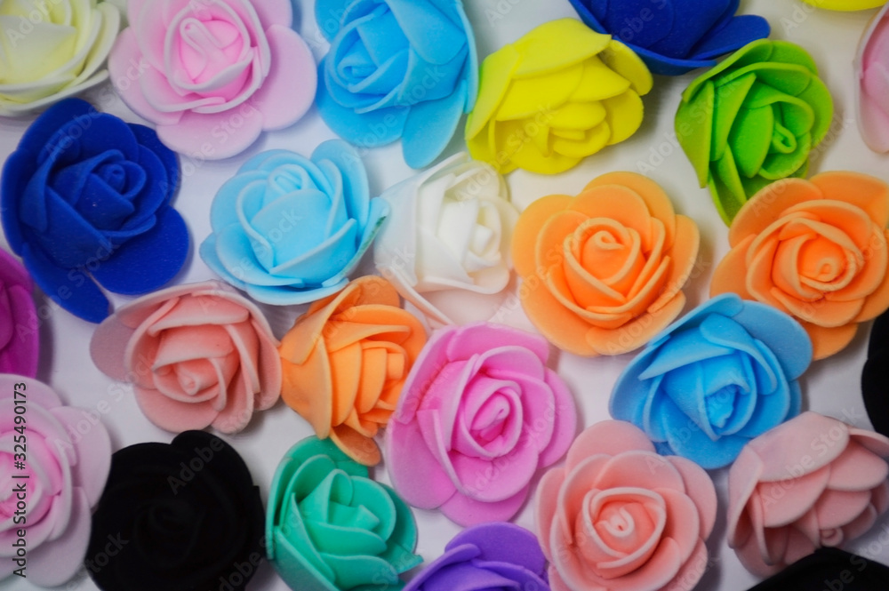 artificial roses of different colors lie on a white background. rose - queen of flowers artificial roses of different colors lie on a white background. rose - queen of flowers