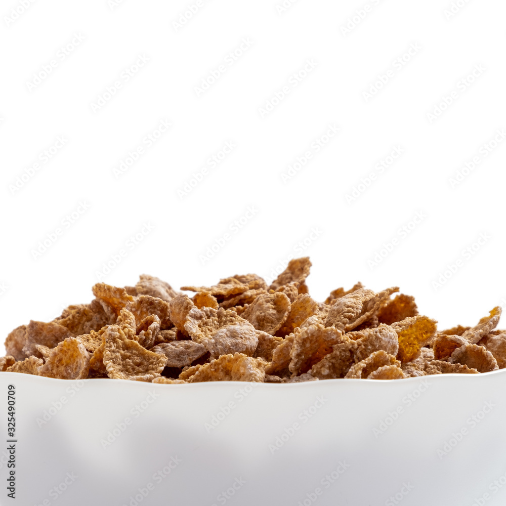 Natural whole grain wheat flakes in white bowl. Healthy breakfast concept. Plate with multigrain flakes on white background Natural whole grain wheat flakes in white bowl. Healthy breakfast concept. Plate with multigrain flakes on white background