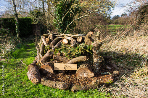 Bug Hotel.  A construction of logs, branches and woodchips made by a local youth club to provide a suitable environment for wild insects in Holt Wiltshire
