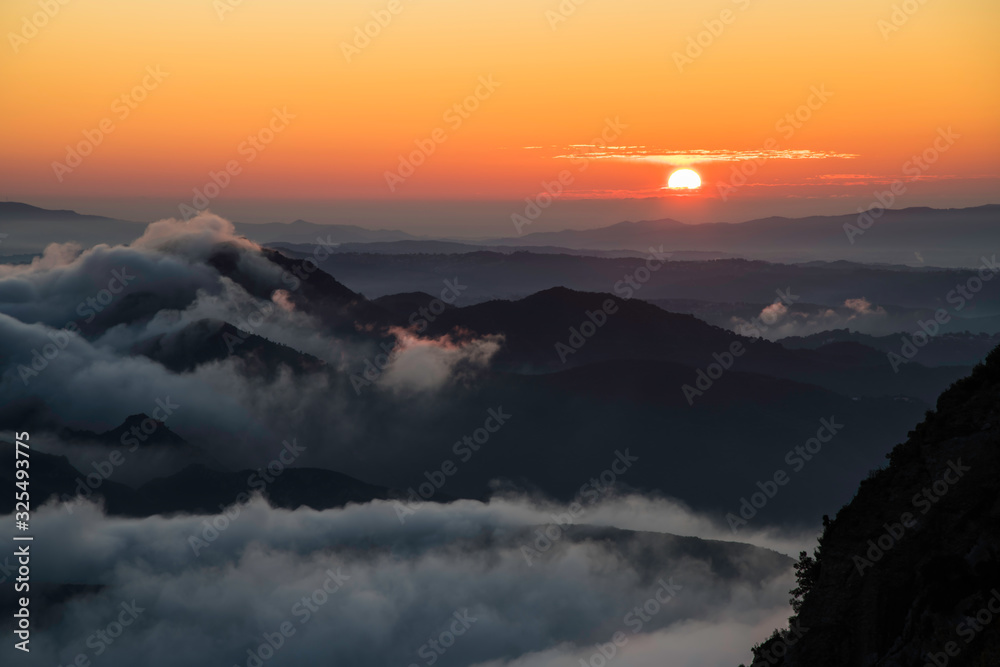 Image of mountains at sunrise with the first rays of the sun on the horizon with warm colors