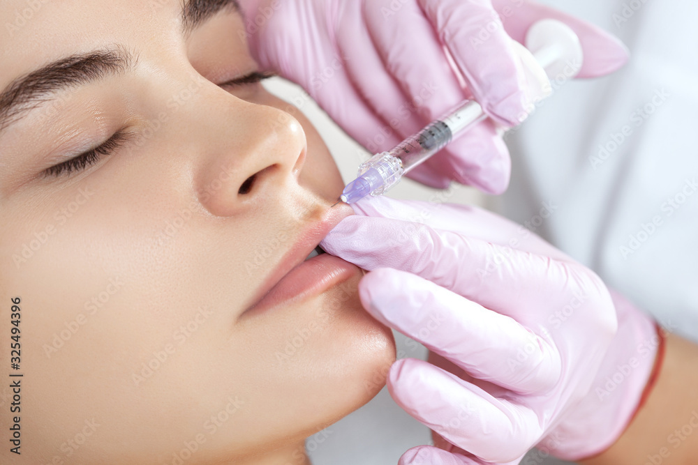 The doctor cosmetologist makes Lip augmentation procedure of a beautiful woman in a beauty salon. Prp therapy, anti wrinkle and aging skin. Cosmetology skin care. The doctor cosmetologist makes Lip augmentation procedure of a beautiful woman in a beauty salon. Prp therapy, anti wrinkle and aging skin. Cosmetology skin care.