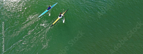 Aerial drone ultra wide photo of young athletes rowing in canoe competition in tropical lake with emerald waters