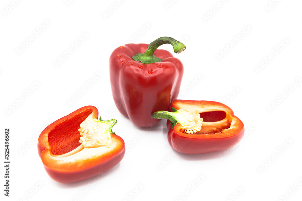 Ripe fresh organic peppers and two halves of pepper in dew drops isolated on a white background Ripe fresh organic peppers and two halves of pepper in dew drops isolated on a white background