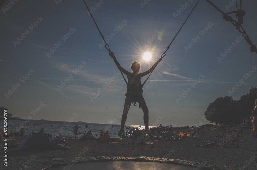 active child in bungee jumping trampoline at sunset active child in bungee jumping trampoline at sunset