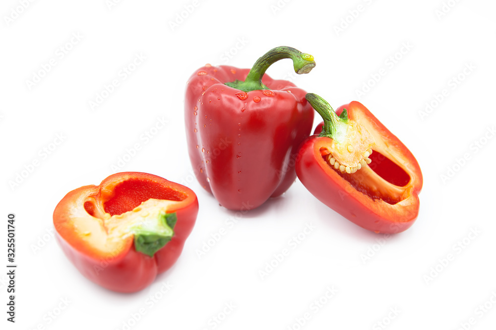 Ripe fresh organic peppers and two halves of pepper in dew drops isolated on a white background Ripe fresh organic peppers and two halves of pepper in dew drops isolated on a white background