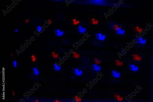 Interesting bokeh in the form of ducks blue and red on a dark background © Konov