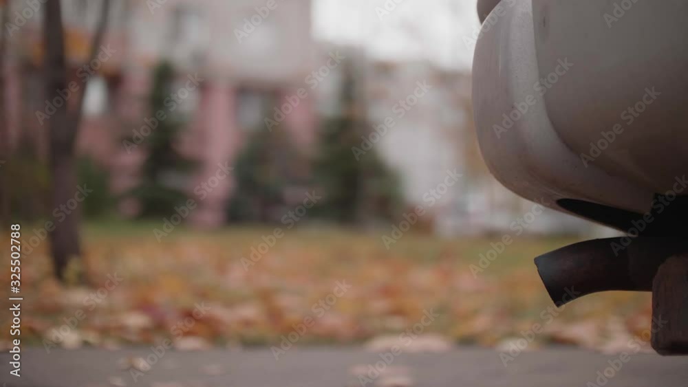 Tail pipe of old car from which cloud of exhaust comes out. Air