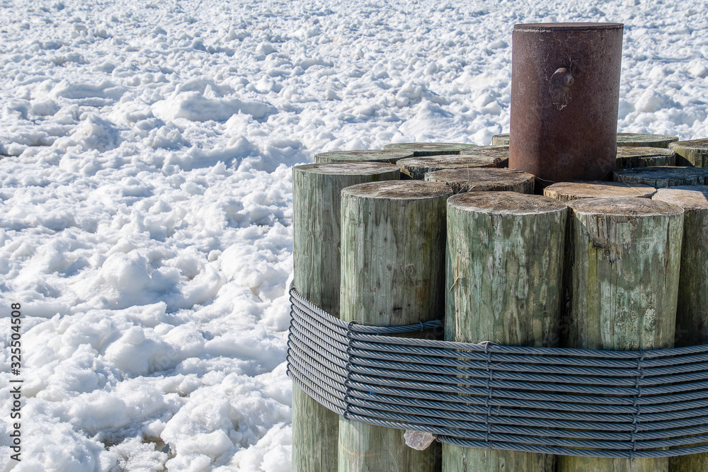 close up of lake pilings secured with steel cable in ice