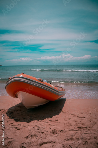 fotograia de un bote posado sobre la arena con mar cristalino de fondo