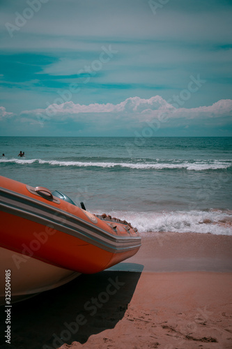 fotograia de un bote posado sobre la arena con mar cristalino de fondo photo