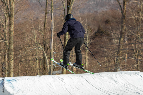 Skier jumping and having fun at resork in winter form the back