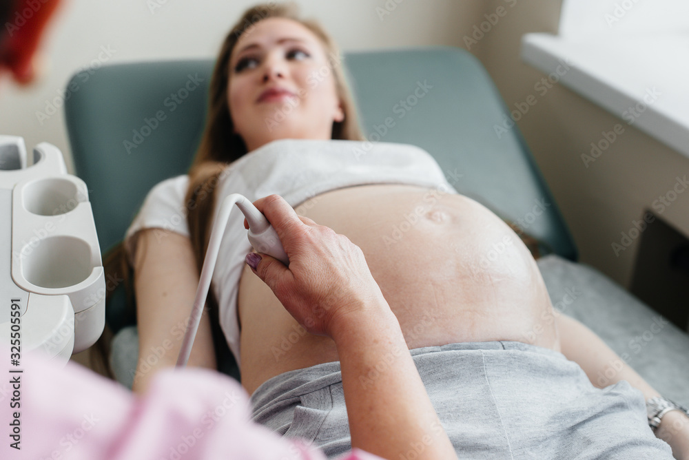 A pregnant girl is having an ultrasound of the abdomen in the clinic in close-up. Medical examination A pregnant girl is having an ultrasound of the abdomen in the clinic in close-up. Medical examination