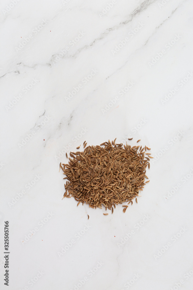 Fototapeta premium Pile of cumin seeds captured from above isolated on white. Seeds of caraway, also known as meridian fennel and Persian cumin. Aromatic carminative. Concept of health and food