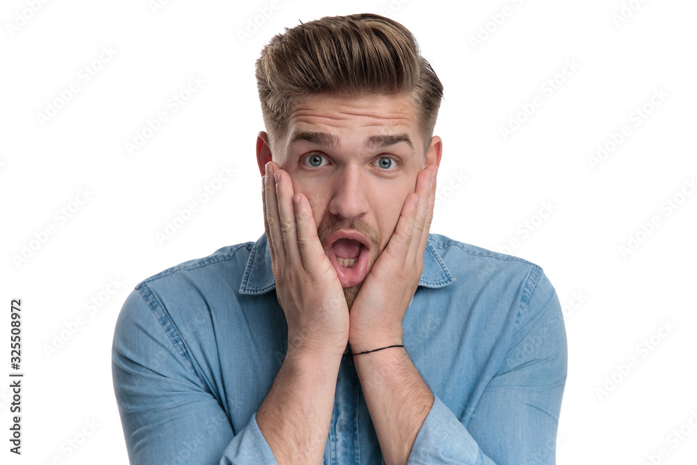 Amazed casual man holding his hand on his face Amazed casual man holding his hand on his face