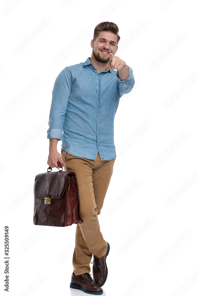 Happy casual man pointing forward, smiling while holding briefcase Happy casual man pointing forward, smiling while holding briefcase