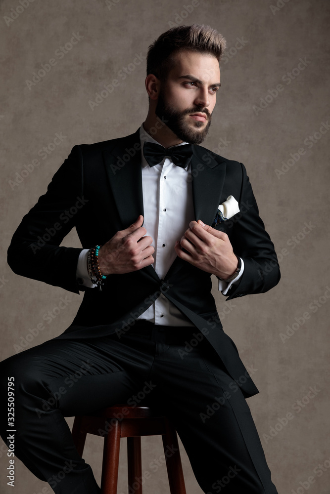 Confident groom adjusting his jacket and looking away Confident groom adjusting his jacket and looking away