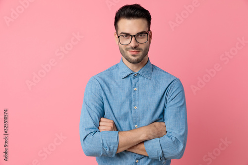 smiling young man crossing arms on pink background