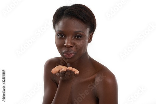 Expressing love. Young half naked african woman sending an air kiss while standing against white background