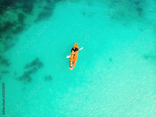 Man and Woman in an orange canoe in tropical waters. Top view from a drone