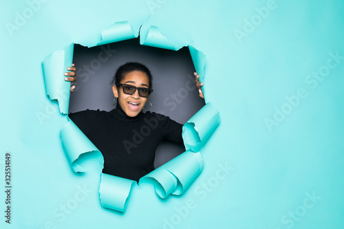 Young smile latin woman in 3d glasses posing from green paper hole © dianagrytsku