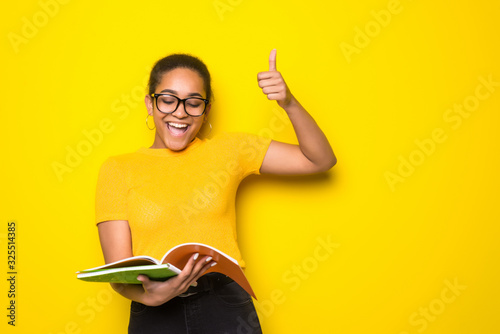 Young latin woman holding note book have idia isolated on yellow background