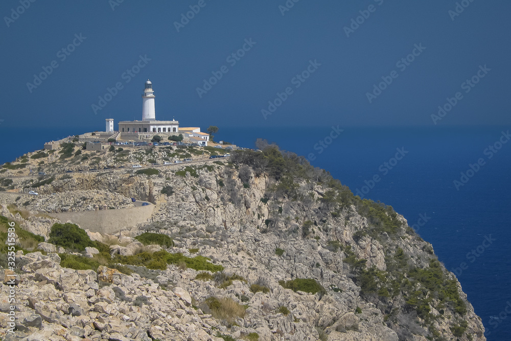 Looking towards the lighthouse on cap Formentor, Mallorca, Spain on a sunny summer day. A lot of rocks in the foreground.and a road leading to the lighthouse.