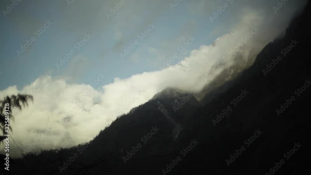 Clouds on mountain with snowy peaks and blue sky, long shot Clouds on mountain with snowy peaks and blue sky, long shot