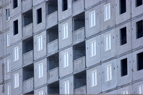 Facade of unfinished high-rise concrete building. Grey skyscraper close up.