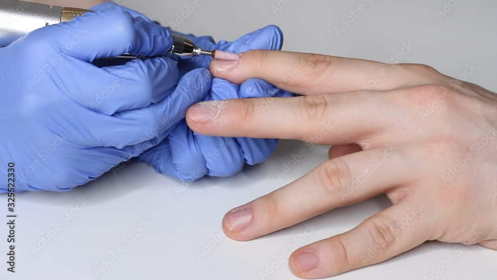 Manicurist in the salon in blue gloves makes a manicure for a man. Manicurist in the salon in blue gloves makes a manicure for a man.