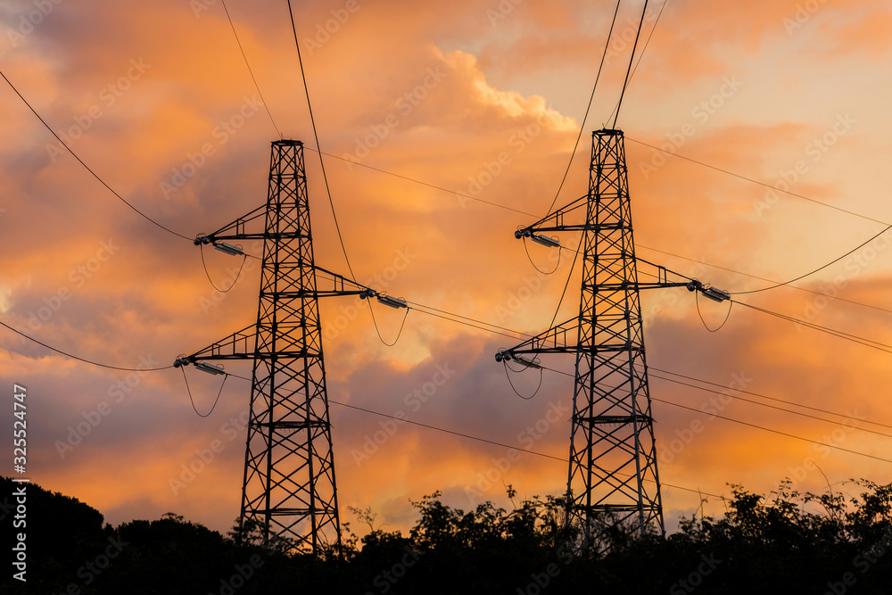Industrial impact on natural environment. Transmission towers or electricity pylons against beautiful sunset clouds