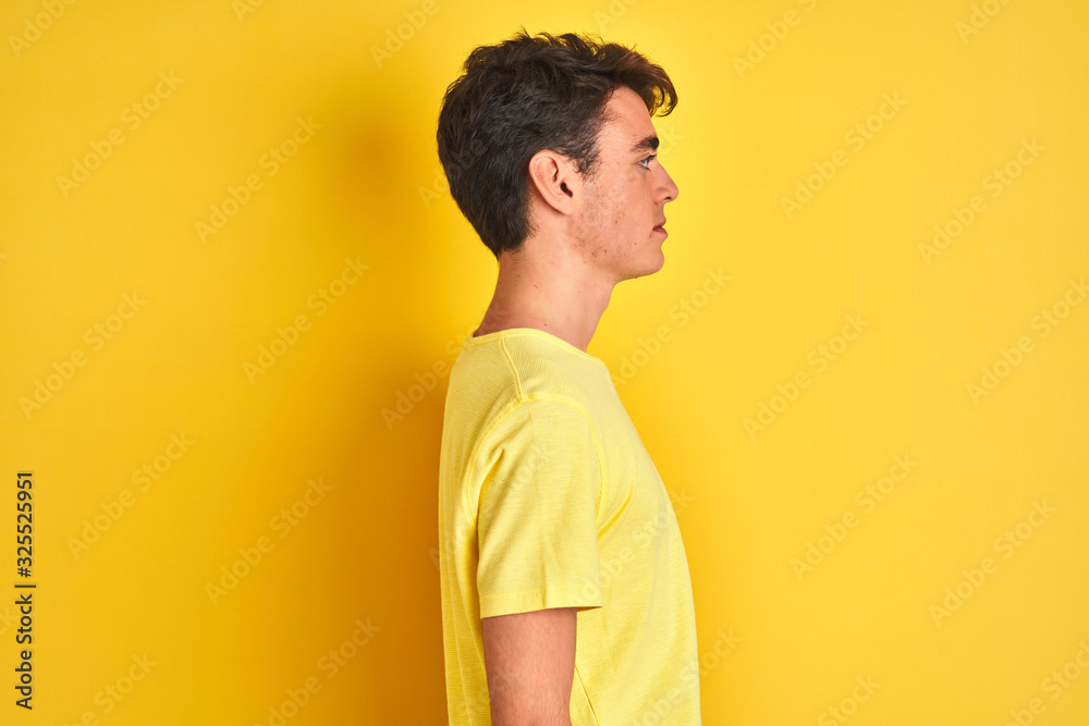 Teenager boy wearing yellow t-shirt over isolated background looking to side, relax profile pose with natural face with confident smile. Teenager boy wearing yellow t-shirt over isolated background looking to side, relax profile pose with natural face with confident smile.