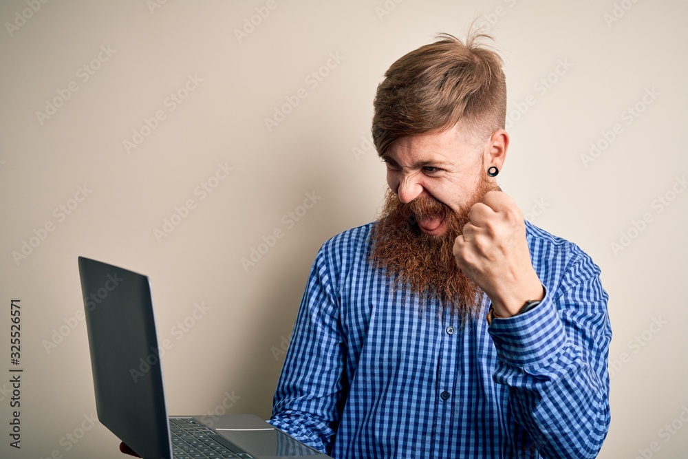 Redhead Irish business man with beard using computer laptop over isolated background screaming proud and celebrating victory and success very excited, cheering emotion Redhead Irish business man with beard using computer laptop over isolated background screaming proud and celebrating victory and success very excited, cheering emotion